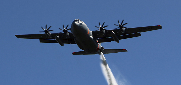 A large plane with four propellers flies overhead